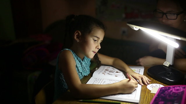 teen girl in the evening doing homework lessons draws light from