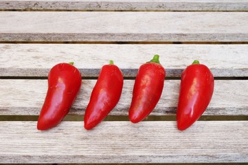 Four red hot chili peppers on a wooden table