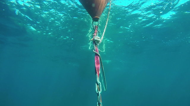 slow motion diving and observing floating orange buoy anchor under surface of Adriatic sea