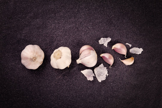  a still life arrangement of Three whole garlic bulbs grouped on