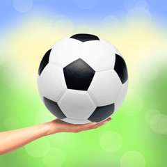 Fototapeta premium Hand holding soccer ball over bright nature background