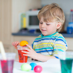 Little kid boy coloring eggs for Easter holiday