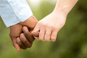 Love.  Rear view of a multiracial couple holding hand.