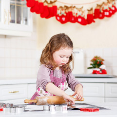 Little girl baking gingerbread cookies in domestic kitchen