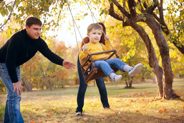 Happy family having fun on a swing ride at a garden a autumn day