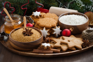 Christmas cookies and ingredients for baking on wooden tray