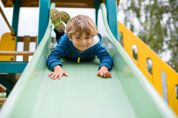 kid boy having fun and sliding on outdoor playground