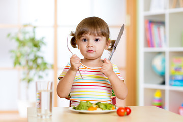 little girl with fork and knife ready to eat