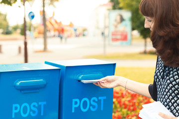 A woman puts letters in the mailbox
