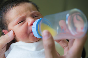 Bebé recién nacido en etapa de lactancia toma primer biberón de leche de apoyo ofrecido por la...