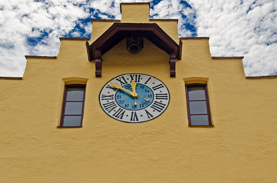 Roman numerals clock on building wall with blue sky 