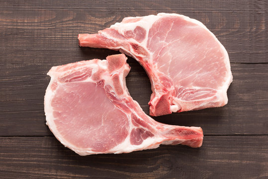 Top view raw pork chop steak on wooden background