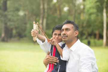 indian father and son playing slingshot at the park