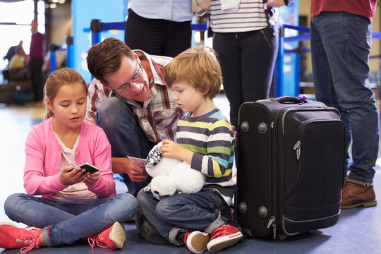 Family Wait In Queue At Airport Check In