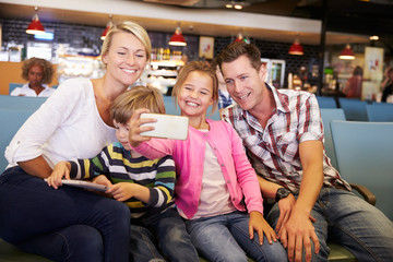 Family In Airport Departure Lounge Waiting To Go On Vacation