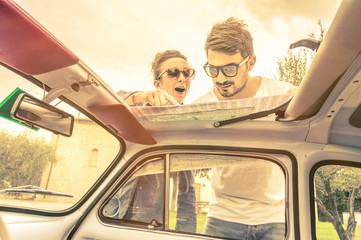 Couple in love looking at map on car during honeymoon road trip vacation