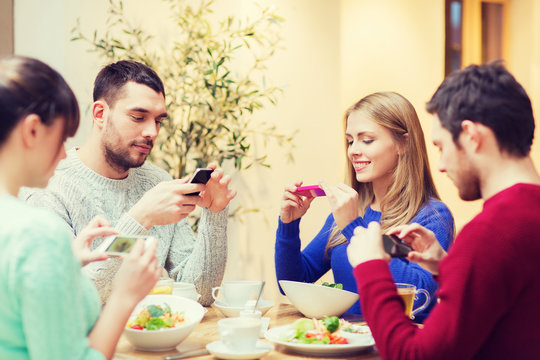 friends with smartphones taking picture of food