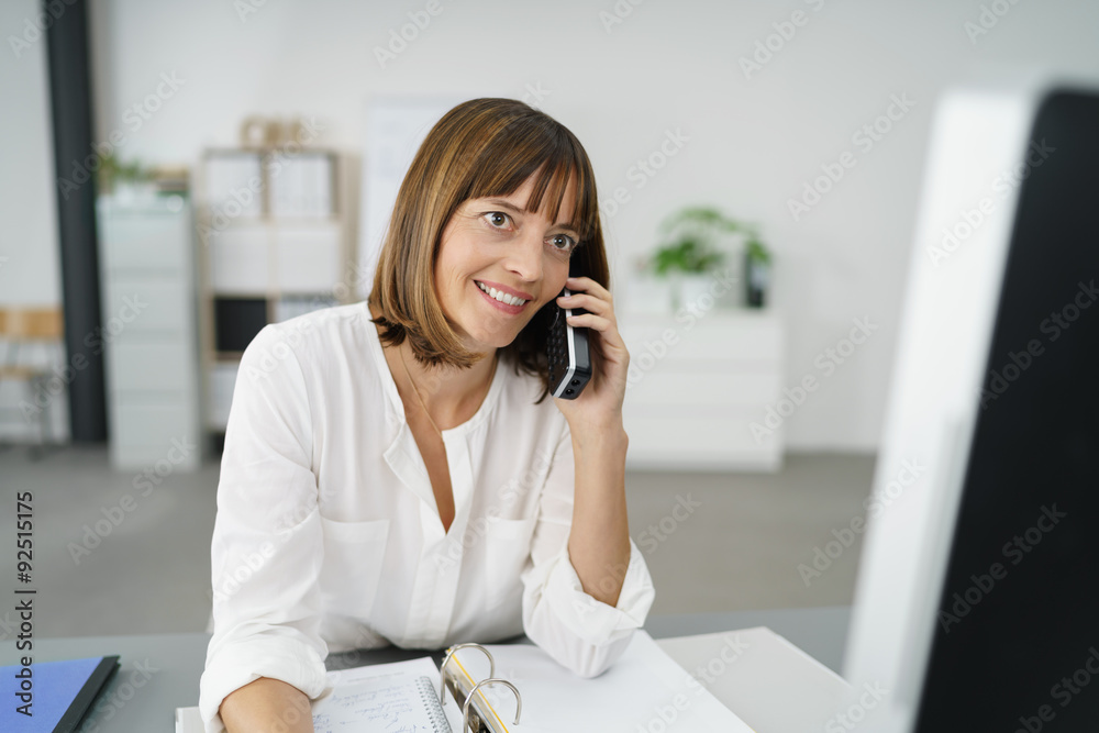 Wall mural frau sitzt am schreibtisch im büro und telefoniert