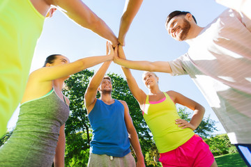 group of happy friends making high five outdoors