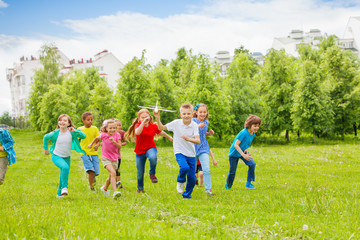Obraz premium Running boy with airplane toy and children behind
