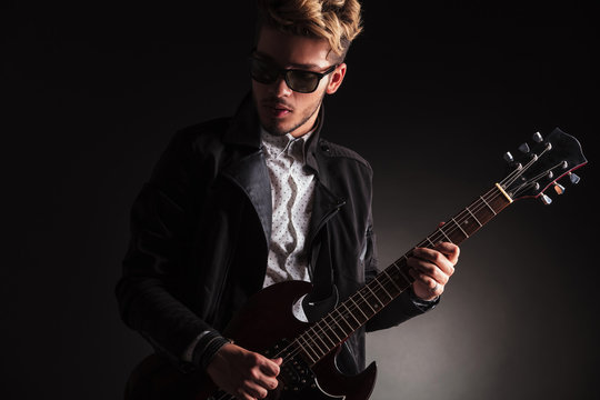 cool young guitarist playing his electric guitar