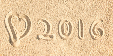 Close up on 2016 written in the sand of a beach with a heart