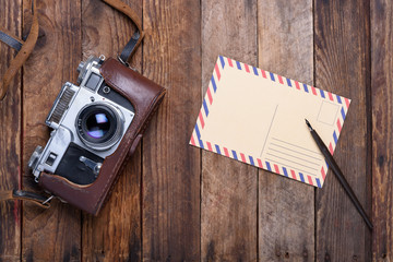Vintage post card and retro camera on old wooden table