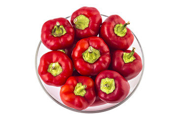 Fresh hot red bell peppers in glass bowl, top view, isolated on white background