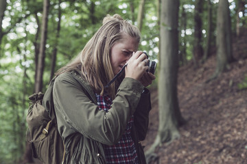 Woman taking pictures in forest.