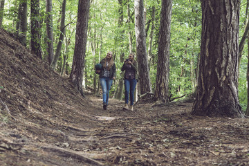 Obraz premium Twin sister walking on forest trail. Walking towards camera.