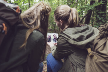 Obraz premium Twin sister making selfie in forest. Over shoulder shot.