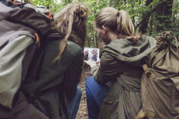 Twin sister making selfie in forest. Over shoulder shot.