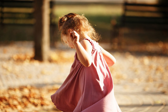 Portrait of a little girl dancing in the park a warm autumn even