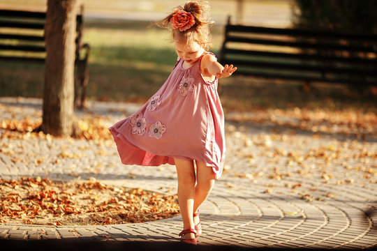 Full length portrait of a little girl dancing in the park a warm