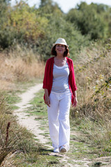 relaxed aging woman walking in a path enjoying summer