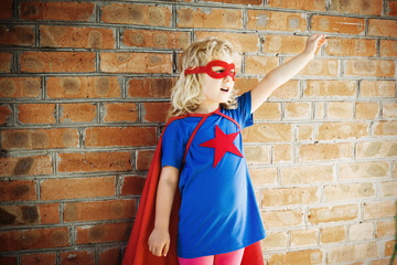 Obraz na płótnie Canvas Cute little super hero girl against brick wall. Superhero concep