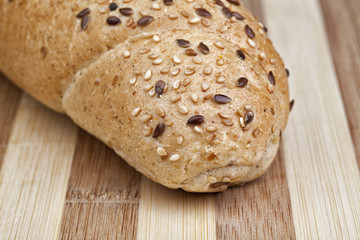 Closeup photo of rye roll mixed from many different healthy ingredients like pieces of soy, rye and wheat flour, sunflower seeds, barley and sesame. Studio shot. 