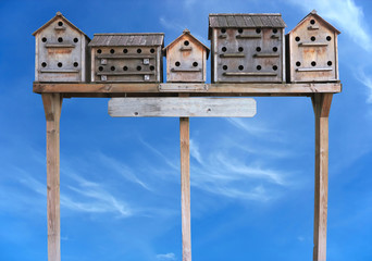 Old wooden starling nesting boxes bird house over blue sky