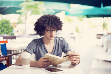 Young man reading book in cafe