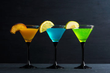 Cocktails garnished with fruits on the black wooden background
