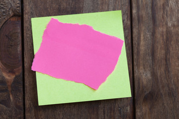 Multicolored paper stickers note on wooden background.