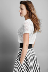 Fototapeta premium Portrait of a beautiful girl in a striped skirt in a studio on a gray background
