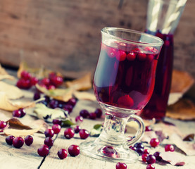 Hot mulled wine with cranberries on the background of autumn, se