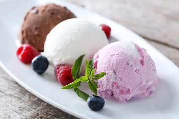 Ice cream on plate with berries on grey wooden background