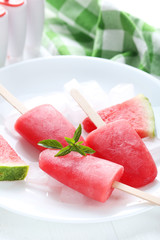 Watermelon popsicle on plate on white wooden table
