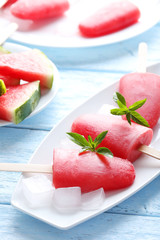 Watermelon popsicle on plate on blue wooden table