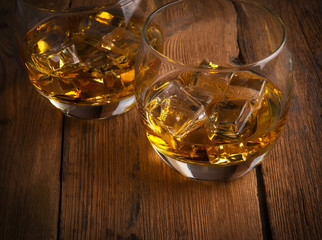 Glowing cognac or brandy in an elegant snifter glass on an old dark wooden bar counter with copyspace