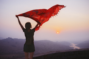 Portrait of a young girl who is waving a handkerchief at dawn in the mountains