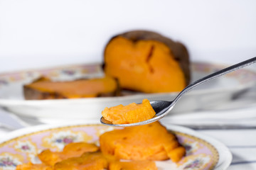 Spoonful of roasted sweet potato in front of dish and tray