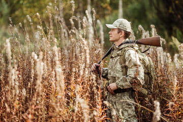 man hunter with shotgun in forest